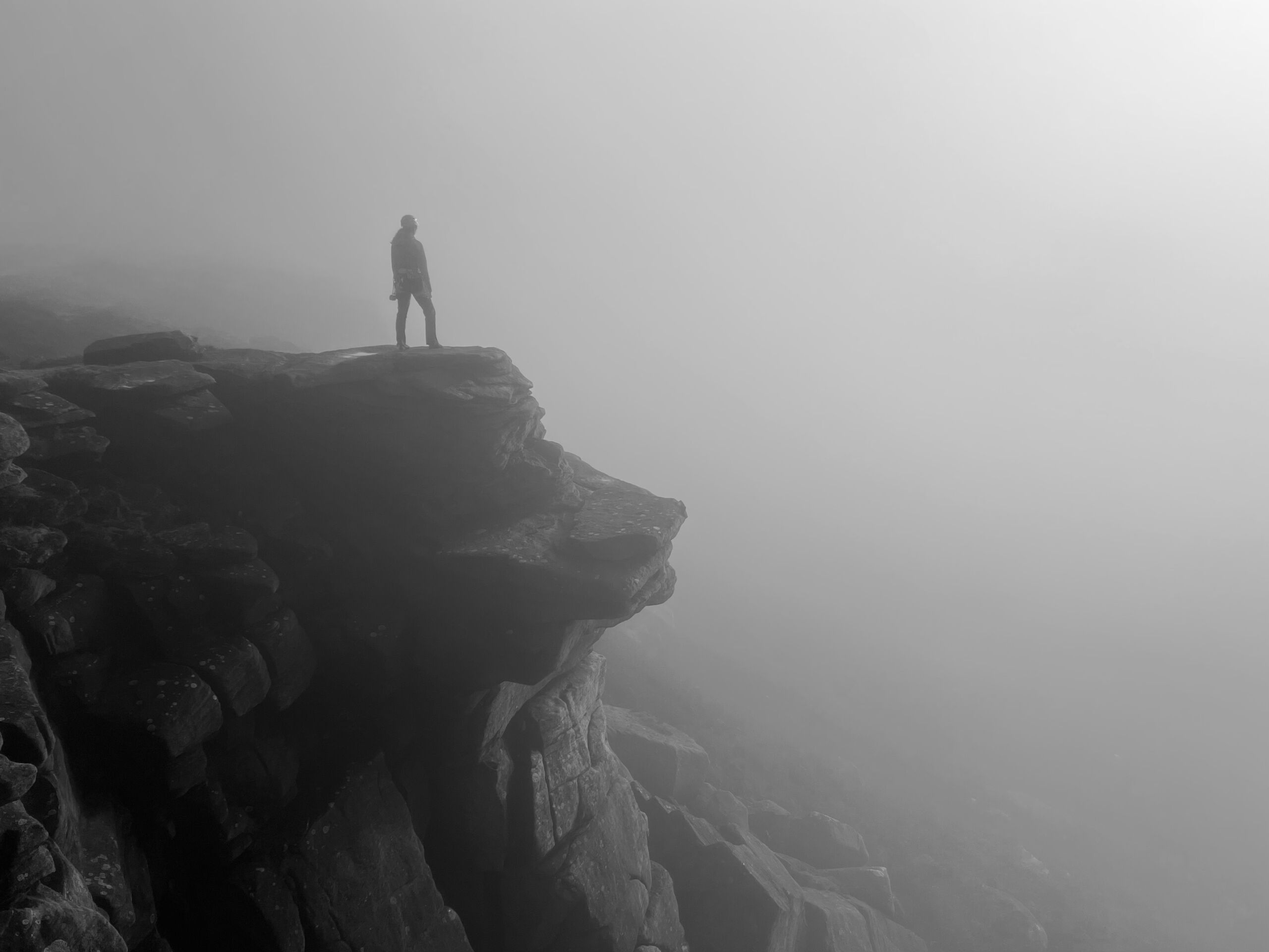 A woman managing fear, standing on the edge of a cliff